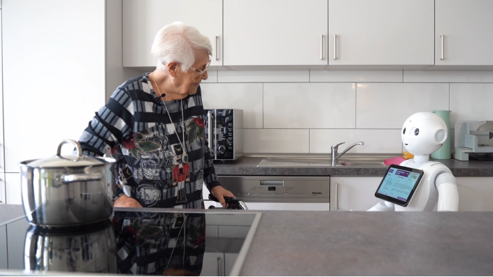 Eine Dame steht mit Pepper dem Roboter in der Küche