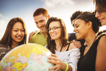 Studierende aus unterschiedlichen Nationen stehen um eine Weltkugel