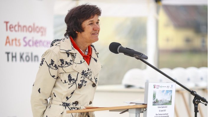 Vera Rottes am Rednerpult – im Hintergrund das Logo der TH Köln