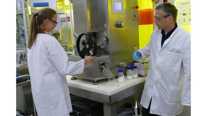 Professor Dr. Richard Hirsch mit einer Besucherin an der Tablettiermaschine