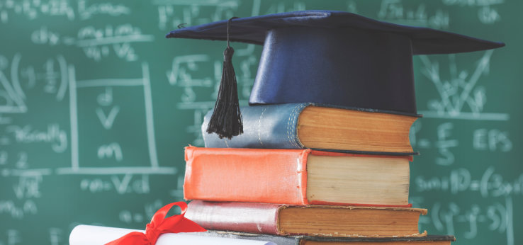  Stack books graduate hat and diploma in front of green chalkboard (Bild: 196875700_sebra_AdobeStock_)