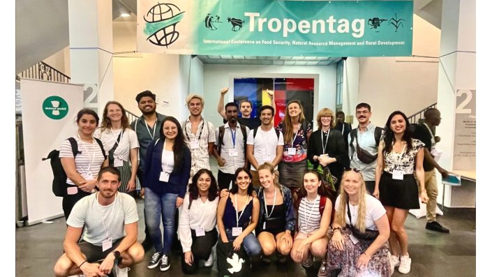 Group of students in front of a building underneath a signal saying "Tropentag"
