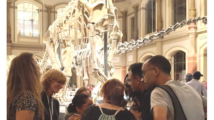 Eine Gruppe Studierender steht in einem Museum vor einem Dino-Skelett
