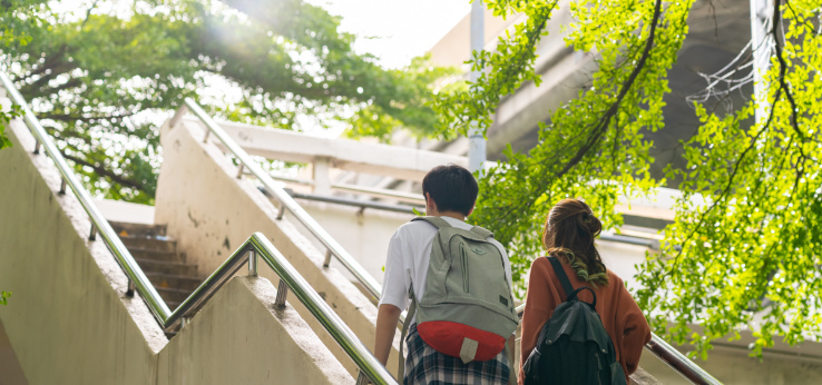 Zwei Studierende gehen eine Außentreppe an einem Gebäude hoch (Bild: AdobeStock_626429974_CandyRetriever)