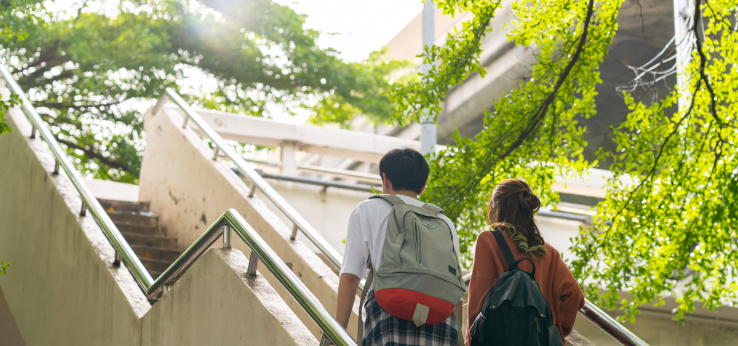 Zwei Studierende gehen eine Außentreppe an einem Gebäude hoch (Bild: AdobeStock_626429974_CandyRetriever)