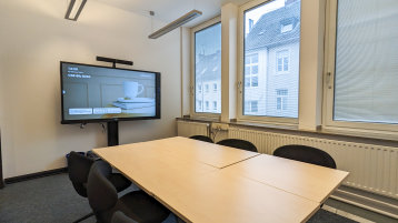 Blick in den Gruppenraum. Zu sehen sind kleine mobile Tische und Stühle. Vorne an der Wand ist ein SmartBoard installiert. (Bild: TH Köln/ Anja Kremser)