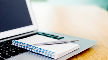 Laptop mit Notizblock und Stift (Bild: iStock-519189026)