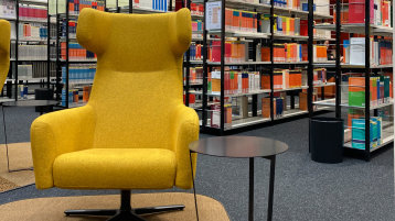 Ein gelber Sessel lädt zwischen den Bücherregalen zum verweilen ein (Bild: TH Köln/ Alina Beier)