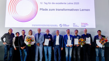 Elf Personen stehen auf der Bühne, einige halten einen Blumenstrauß oder einen Preis. Über ihnen eine Präsentation: "12. Tag für die exzellente Lehre: Pfade zum transformativen Lernen" (Bild: Thilo Schmülgen/TH Köln)
