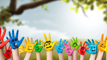 Bunt bemalte Kinderhände strecken sich in die Luft (Bild: Fotogestoeber / Adobe Stock)