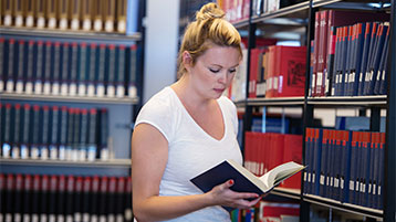 Junge Frau vor Bücherregal Junge Frau vor Bücherregal