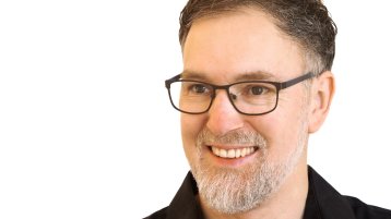 Jürgen Sleegers trägt ein schwarzes Hemd, eine schwarze Brille und dunkelbraune Haare. Er befindet sich vor einem weißen Hintergrund. (Bild: Sleegers)