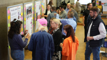 Vor einer Reihe an Pinnwänden stehen zahlreiche Personen und unterhalten sich in Kleingruppen.  (Bild: ZLE / TH Köln)