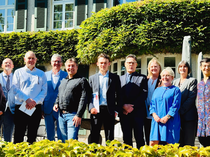 Ein Gruppenbild der Preisträgerinnen. Die Gruppe ist zentriert und steht vor der begrünten Fassade eines Hauses