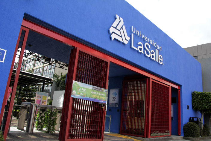 Eingang der Universidad La Salle in Mexiko mit blauem Gebäude, weißem Logo und Schriftzug sowie roten Eingangstoren.