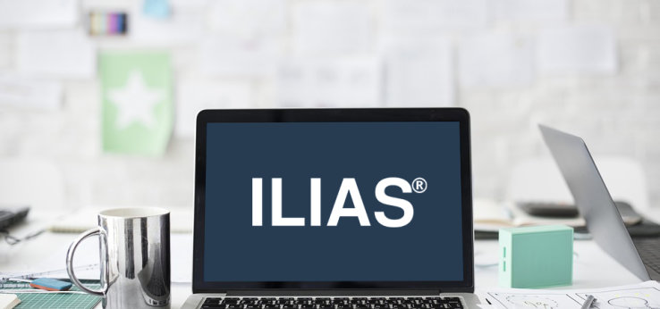 Ein silberner Laptop auf dem das Logo der Firma ILIAS zu sehen ist, im Hintergrund ein Arbeitsplatz (Bild: Medienbüro ZLE)