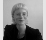 Monochromes Bild, Rose Beauchamp hat blonde, vorne kurze und hinten lange Haare. Sie trägt eine runde Brille und eine schwarze Jacke.