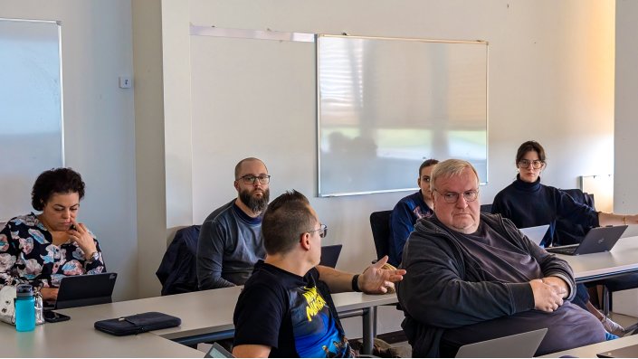 Mehrere Mitglieder der CoE hören aufmerksam zu während Michael Lenhart spricht.