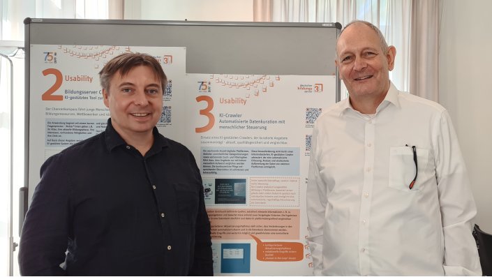 Terence Droste und Detlev Richter vor dem Poster zum dritten Platz für den "KI-Crawler"