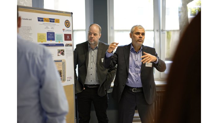 Rechts neben ihrem Poster stehen Prof. Dr. Erik Angelone und Prof. Dr. Ali Nazari, der gerade spricht. 