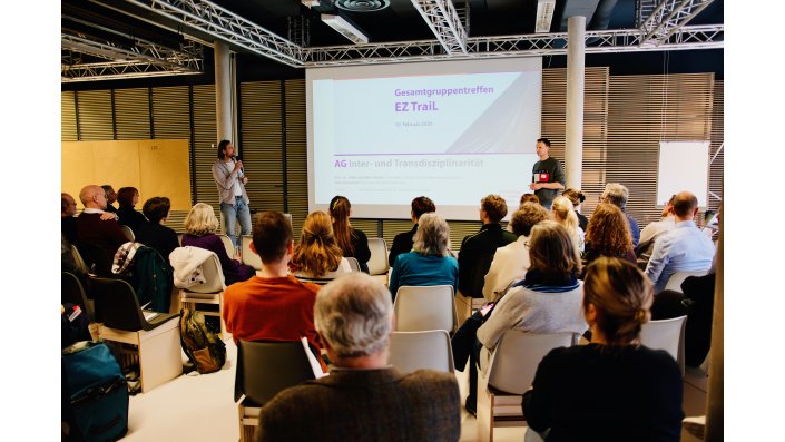 Die Teilnehmenden sitzen halbkreisförmig vor der Leinwand. Auf der Leinwand steht ,,Gesamttruppentreffen EZ Trail – AG Inter- und Transdisziplinarität“ und rechts davon steht Heiko Schiffter-Weinle . Links steht Dirk Heuvemann.