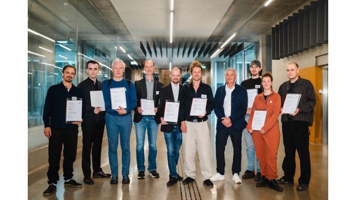 Foto: Neun Personen stehen nebeneinander, halten Urkunden in den Händen und blicken in die Kamera.