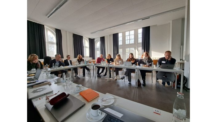 Tables positioned in a U-Form with multiple people sitting at them and working together during a workshop.