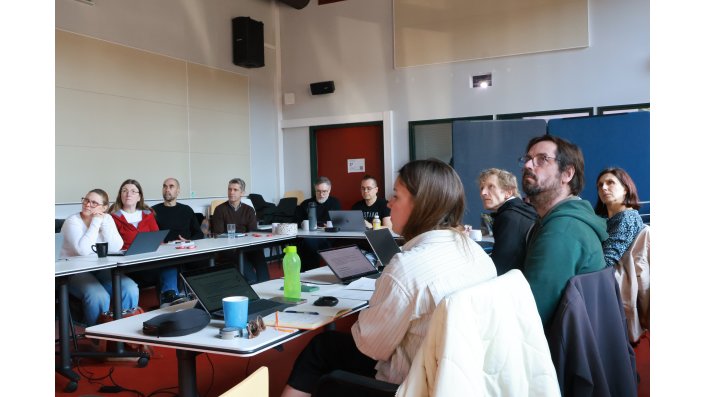 Die Mitglieder der Community of Experts sitzen an Tischen in U-Form und folgen der Veranstaltung. 