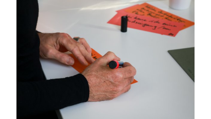 Eine Hand schreibt etwas auf eine Metaplankarte.