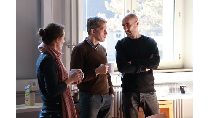 Drei Mitglieder führen bei einer Tasse Kaffee ein Austauschgespräch.