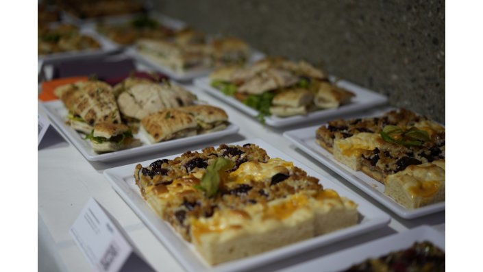 Eine Detailaufnahme des Caterings mit Kuchen im Vordergrund und Sandwiches im Hintergrund. 