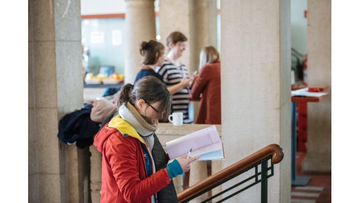 Foto: Frau steigt Treppe hoch und schmökert im Tagungsprogramm