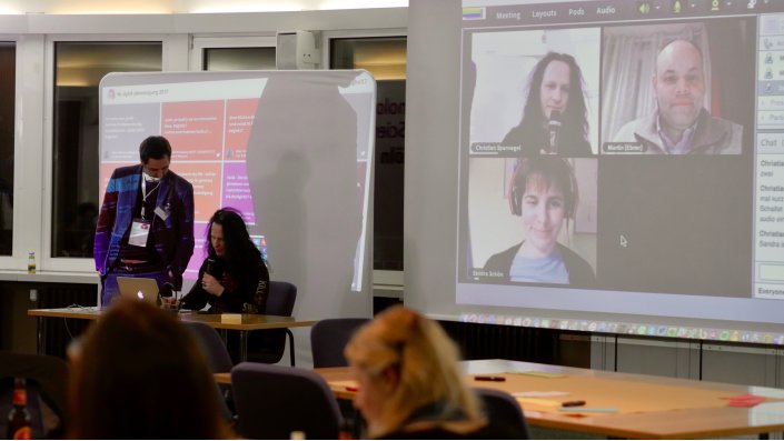 Foto: Zwei Personen vor Twittwall und Noebook, im Hintergrund Connect-Raum mit Chrisitan Spannagel, Martin Ebner und Sandra Schön