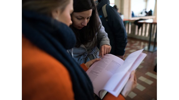 Foto: Menschen über das Programmheft der Tagung gebeugt