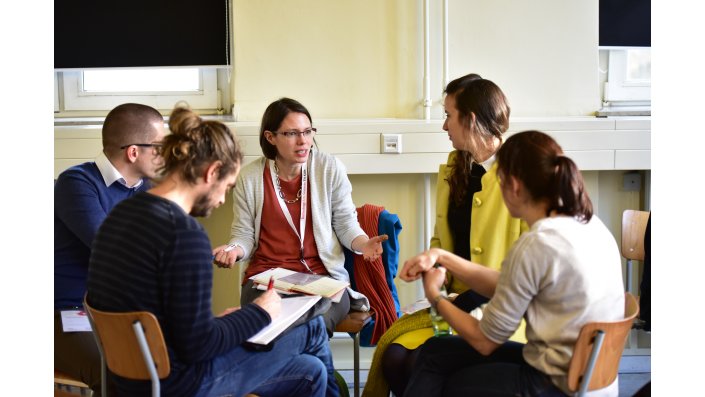 Foto: mehrere Personen diskutieren angeregt im Stuhlkreis