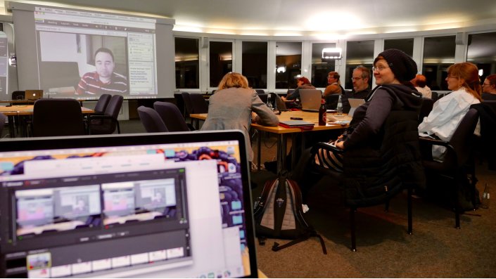 Foto: Moshe Leiba auf der Videowand, mherere Teilnehmer_innen in der Rotunde an den Tischen