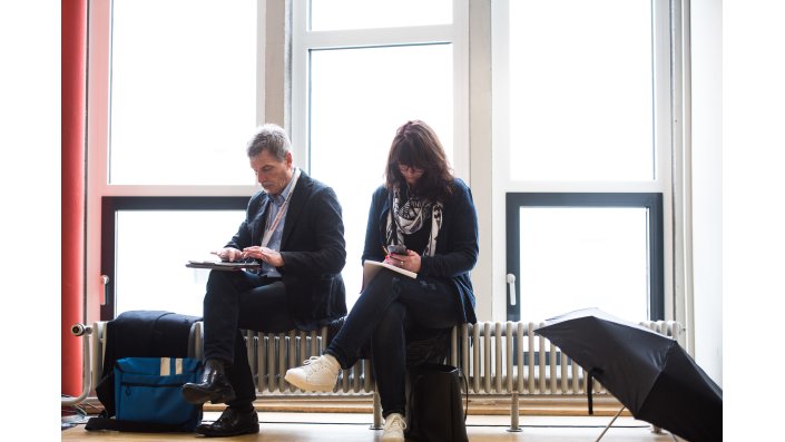 Foto: Teilnehmende sitzen auf Heizkörpern im Hörsaal, daneben Regenschirme