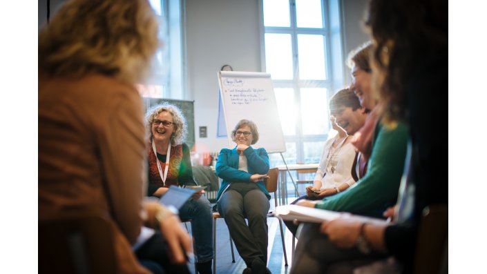 Foto: Diskussion im Stuhlkreis mit Flipchart im Hintergrund