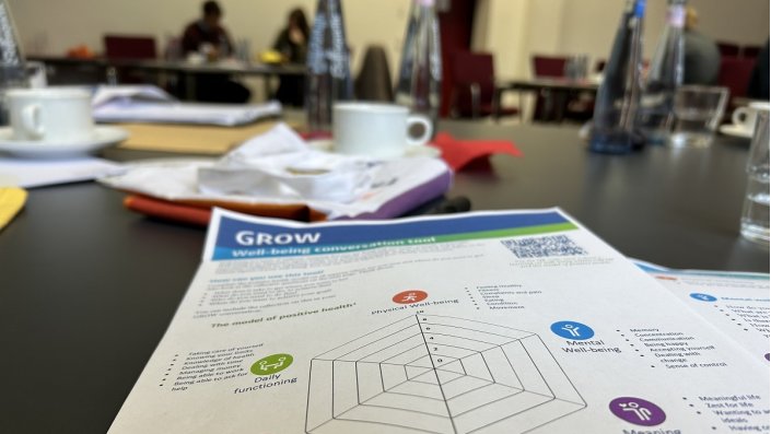 Arbeitsblatt auf einem Tisch, im Hintergrund Personen an einem Tisch