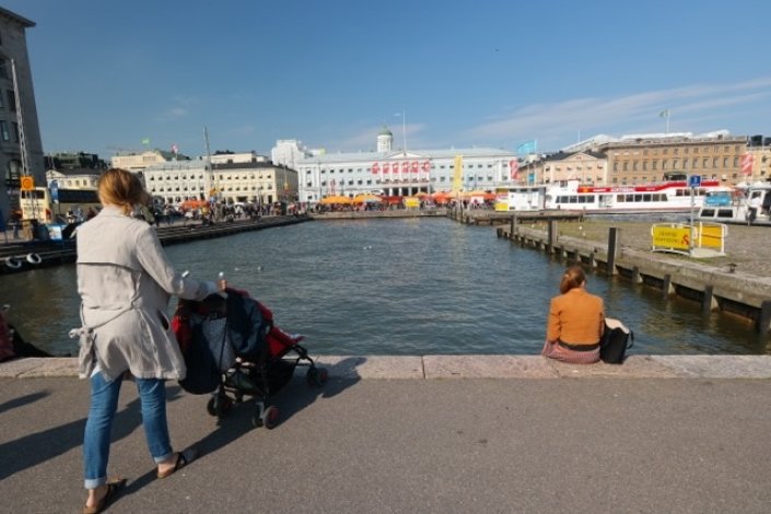 Mutter geht mit Kind im Kinderwagen bei sonnigem Wetter in Helsinki spazieren. Mutter geht mit Kind im Kinderwagen bei sonnigem Wetter in Helsinki spazieren.
