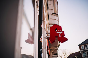 Rotes Apotheken- Logo an einer Hauswand