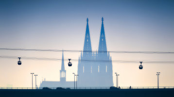 Man sieht die Kölner Seilbahn und im Hintergrund schemenartig den Kölner Dom.  (Bild: Adobe Stock / Tom Bayer)