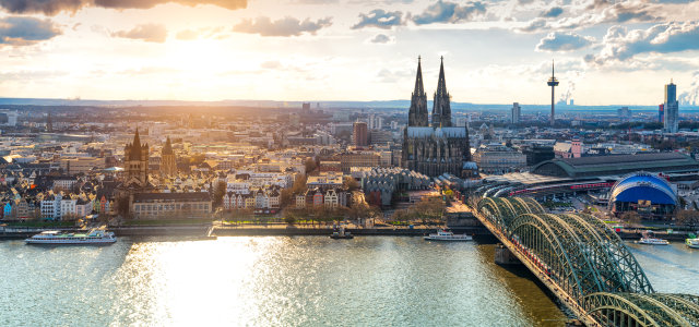 Man sieht Köln bei Tageslicht von oben, der Dom prominent in der Mitte, die Hohenzollernbrücke und angrenzende Gebiete. (Bild:Adobe Stock / Simon)
