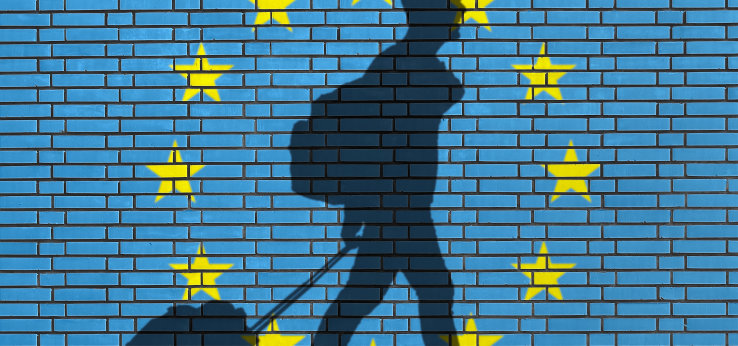 Travel in European Union, Person with luggage in front of blue wall with EU stars in yellow. (Bild: Adobe Stock / Jonathan Stutz)