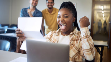 Eine Studentin, die vor einem Laptop sitzt, hält einen Brief in der Hand und freut sich über den Inhalt, sie reckt dabei die Faust nach oben in einer Siegerpose (Bild: Adobe Stock / K Abrahams_peopleimages.com) Eine Studentin, die vor einem Laptop sitzt, hält einen Brief in der Hand und freut sich über den Inhalt, sie reckt dabei die Faust nach oben in einer Siegerpose (Bild: Adobe Stock / K Abrahams_peopleimages.com)