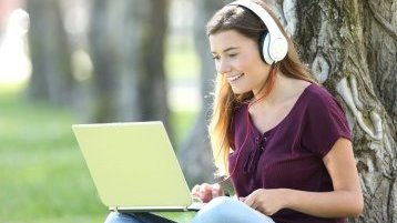 Eine Studentin sitzt mit einem Laptop vor einem Baum (Image: Colourbox.de)