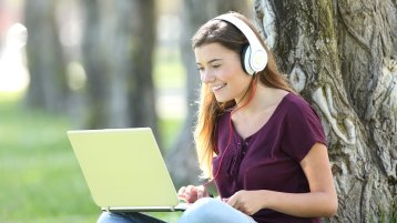 Eine Studentin sitzt mit einem Laptop vor einem Baum (Bild: Colourbox.de)