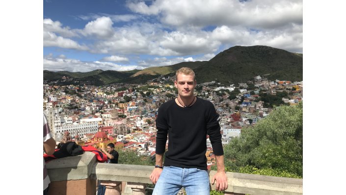 Der Student Christopher Schady sitzt auf einer Mauer, im Hintergrund sieht man die Stadt Guanajuato