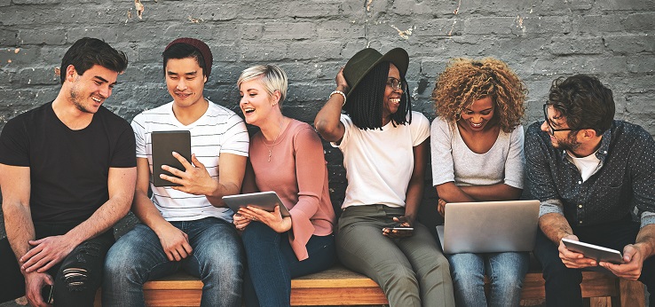 Sechs Studierende sitzen mit Laptops und Tablets auf einer Bank (Bild: iStock)