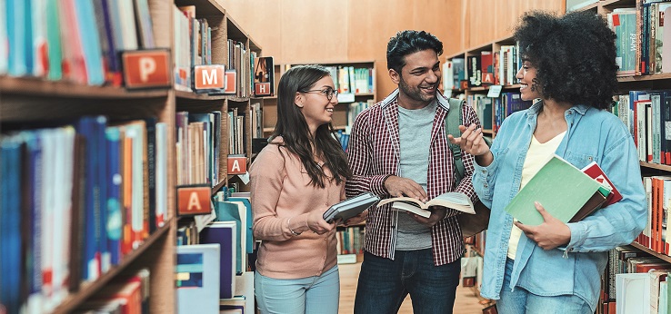 Drei Studierende unterhalten sich in der Bibliothek (Bild: iStock)